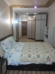 Un dormitorio con una cama grande con una manta de flores en Apartment in the 7th Microdistrict en Bishkek