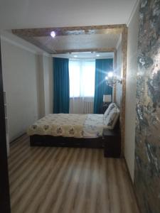 1 dormitorio con cama y ventana en Apartment in the 7th Microdistrict, en Bishkek