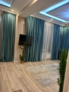 a living room with blue curtains and a flat screen tv at Вилла в г.Кусары in Qusar