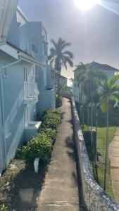 a sidewalk next to a blue building with palm trees at Ya mon inn in Negril