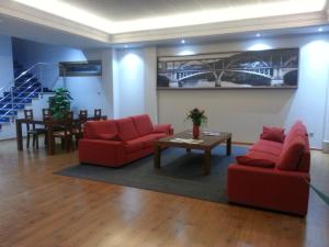 a living room with two red chairs and a table at Hotel San Cibrao in San Ciprián de Viñas