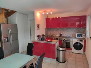 cocina con armarios rojos, mesa y sillas en Maison/Parking Privé/Piscine/Wifi/Canal du midi, en Béziers