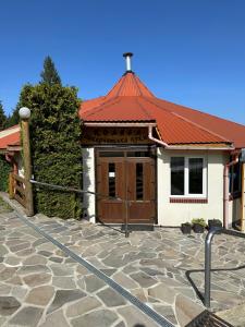 a building with a red roof and a stone patio at Guest House Podobovets 2000 in Podobovets