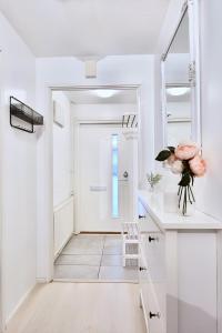 a white hallway with a door and a vase of flowers at Cozy 93m² Townhouse with Large Terrace & Sauna in Turku