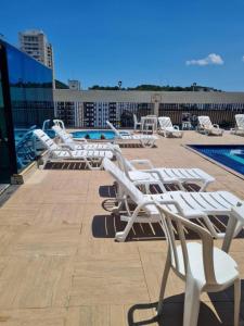 a row of white lounge chairs on a roof at Flat Palladium São Vicente in São Vicente