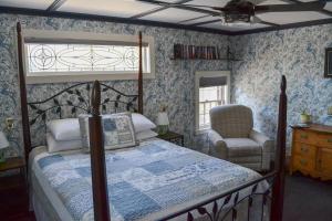 ein Schlafzimmer mit einem Himmelbett und einem Stuhl in der Unterkunft Black Friar Inn and Pub in Bar Harbor