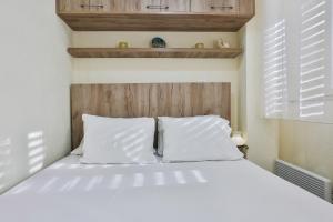 uma cama branca com almofadas brancas num quarto em Basilica Apartments em Budva