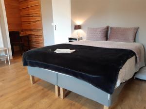 a bed with a black blanket on it in a room at Manoir Saint-Pardoux 63680 in La Tour-dʼAuvergne