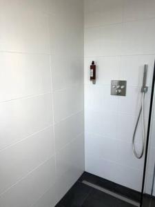 a bathroom with a shower with a white wall at Wohnung am CentrO! in Oberhausen +2 photos