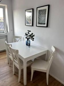 a white dining room table with chairs and a vase with flowers at Wohnung am CentrO! in Oberhausen