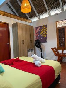 1 dormitorio con 1 cama grande con manta roja en Isla Los Erizos EcoHouse, en Isla Grande