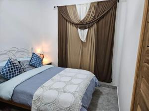 Schlafzimmer mit einem Bett und einem Fenster mit Vorhängen in der Unterkunft Gardens Apartment in Accra