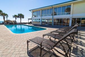 un grupo de bancos junto a un edificio con piscina en Rejuvinating 2nd flr Resort View King Room, en Pawleys Island