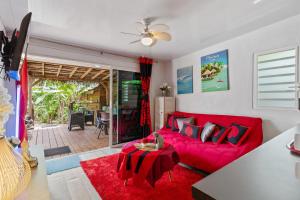 a living room with a red couch and a table at Fare Oaoa Haapiti in Moorea