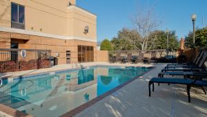 a large swimming pool with lounge chairs next to a building at Russell Inn and Suites in Starkville