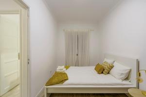 Dormitorio blanco con cama con almohadas amarillas en Apartamento Goa, en Amadora