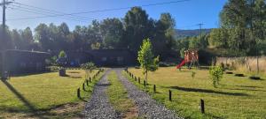 a gravel road in a field with a playground at Cabañas Troncos de Relin in Panguipulli +61 photos