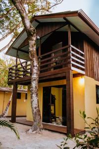 a house with a balcony and a tree at Casa Alegria da Ilha in Paranaguá