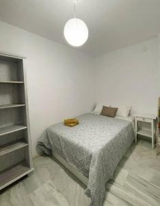 a white bedroom with a bed and a lamp at Acogedor piso a un paso de Granada Capital. in Granada