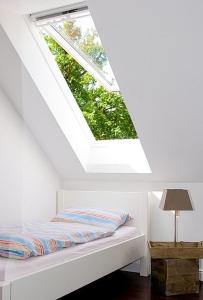 a bed in a white room with a skylight at SEEBADHOF - Landhaus Kaiser in Rangsdorf