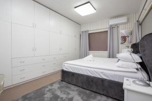 a white bedroom with a bed and a sink at CitySide Pad in Tamworth