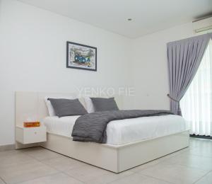 Una cama blanca en una habitación blanca con en Yenko Fie Suites: The Signature Apartments, Accra Ghana en Accra