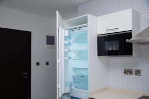 阿克拉的住宿－Yenko Fie Suites: The Signature Apartments, Accra Ghana，厨房里设有冰箱,门开