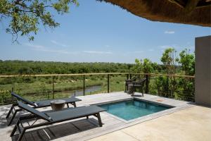 un patio con piscina, mesa y sillas en Leopard Sands Kruger Park, en Skukuza