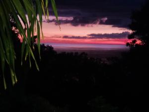 una puesta de sol sobre el océano con árboles en el primer plano en Stephane, en Pointe-Noire