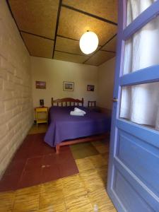 a room with a bed and a blue door at Humahuaca Hostel in Humahuaca