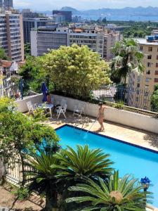 a woman walking by a swimming pool on top of a building at Hostel Sunrise in Rio de Janeiro