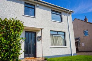 a white brick house with a blue door at The Heather Dew in Portstewart