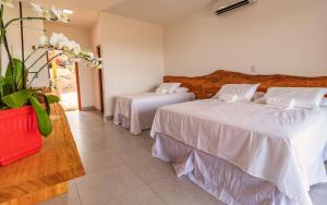 a bedroom with two beds and a vase with flowers at Rancho da Cachaça Pousada in Holambra