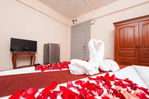 a bedroom with two beds with red roses and swans at Baan Kamala Backpacker in Kamala Beach