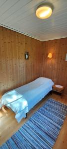 1 dormitorio con 1 cama con edredón azul y alfombra en Strandstua Solbakken Feriehus, en Fevåg