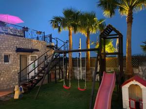 a playground with swings and palm trees next to a building at Socrates Studios in Tigaki