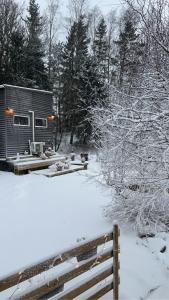 a small cabin in the snow with a fence at 15 min från Ullared! Ny stuga med hög standard! in Älvsered