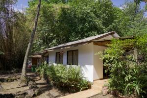 a small white house in the middle of trees at Cabañas moeVarua en Tahai in Hanga Roa