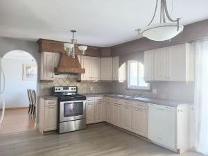 cocina con armarios blancos y fogones en Cozy Home Close to Attractions in Niagara Falls en Thorold