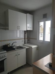 a kitchen with white cabinets and a sink and a window at Nice apartment. Chamartin. La Vaguada.P Castilla in Madrid