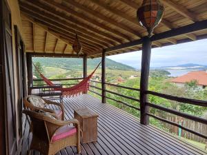 a porch with two chairs and a hammock on it at Casa Morango in Praia do Rosa