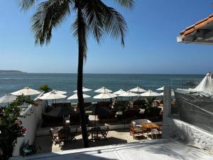 einen Strand mit Tischen und Sonnenschirmen und dem Meer in der Unterkunft Wala beach club in Cartagena de Indias