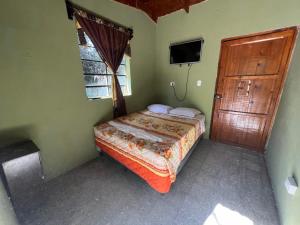 sypialnia z łóżkiem, telewizorem i drzwiami w obiekcie Cabaña de Atitlan w mieście Panajachel