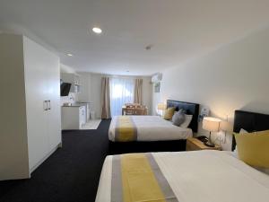 a hotel room with two beds and a kitchen at Royal Park Lodge in Auckland