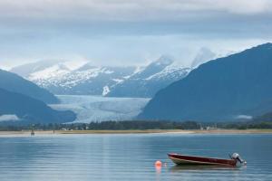 una barca rossa seduta in acqua con le montagne di Douglas Island A-frame Cabin in the Woods a Juneau