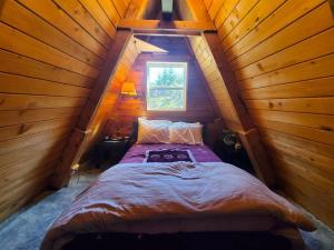 Bett in einem Holzzimmer mit Fenster in der Unterkunft Douglas Island A-frame Cabin in the Woods in Juneau