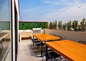balcón con 2 mesas de madera y cocina en New Full Apartment in Barranco en Lima