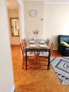 a dining room table with chairs and a clock on the wall at GREAT PARIS, private parking and balcony, 24 hours self checking, near Stade de France in Bondy