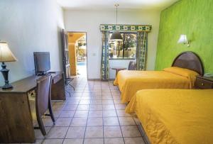una camera d'albergo con due letti e una televisione di Hacienda Suites Loreto a Loreto