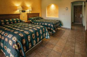 um quarto de hotel com 2 camas e piso em azulejo em Hacienda Suites Loreto em Loreto